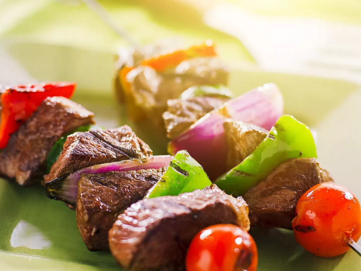 Brochettes de bœuf bien grillé avec ses tomates et lamelles d'oignons. Halal.